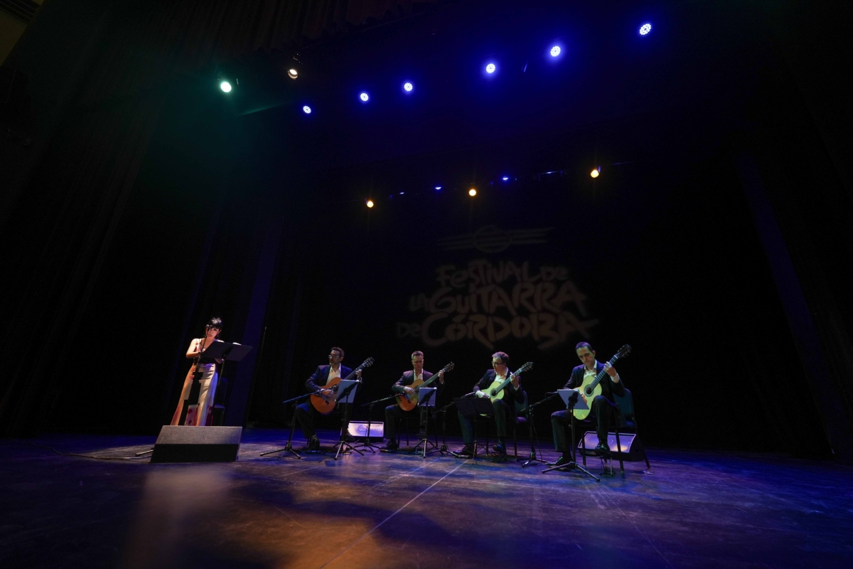 Un grupo de personas tocando guitarras en un escenario con un cartel que dice festival de la guitarra de córdoba