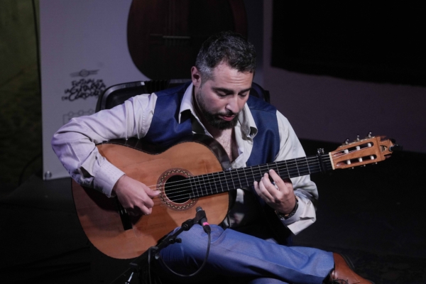 Un hombre toca una guitarra frente a un cartel que dice "españa".